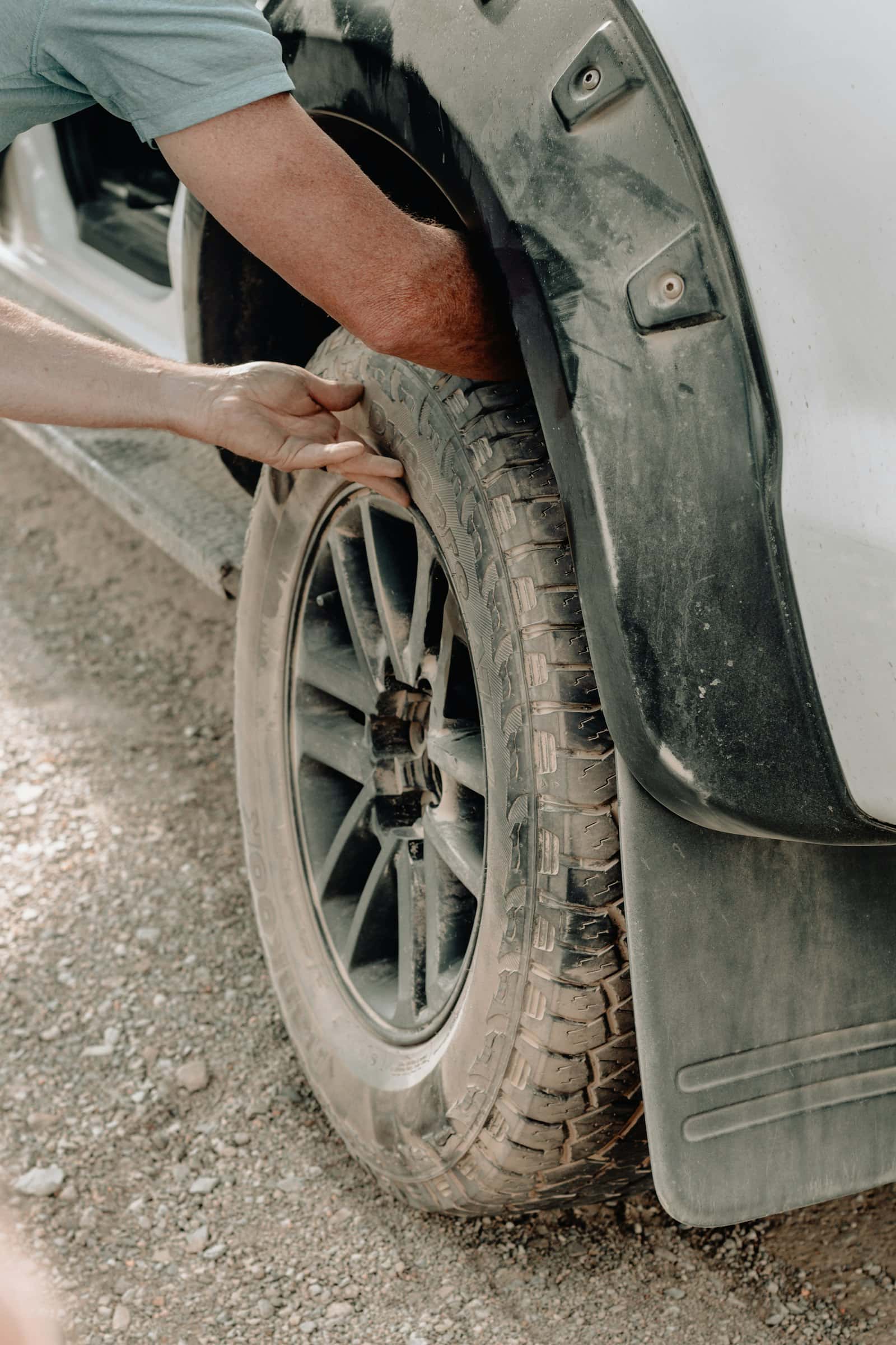 Mobile technician lifting a wheel back onto a pickup stopped on a gravel shoulder, the kind of roadside flat repair Jang drives to across Durham Region, Ontario